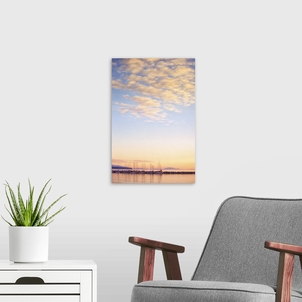 A modern room featuring A photo of blue sky with white fluffy clouds over a body of water with sailboats.