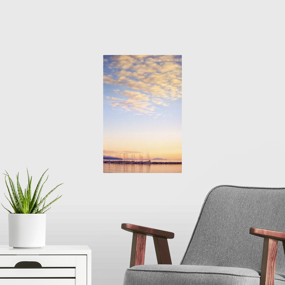 A modern room featuring A photo of blue sky with white fluffy clouds over a body of water with sailboats.