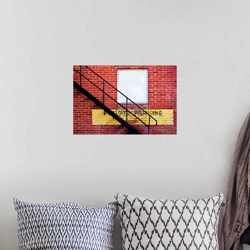 A bohemian room featuring A notice of private parking is painted on a brick wall with metal fire escape stairs.