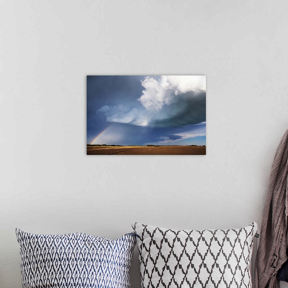A bohemian room featuring Photograph of a prairie landscape with a rainbow formed underneath dark clouds.