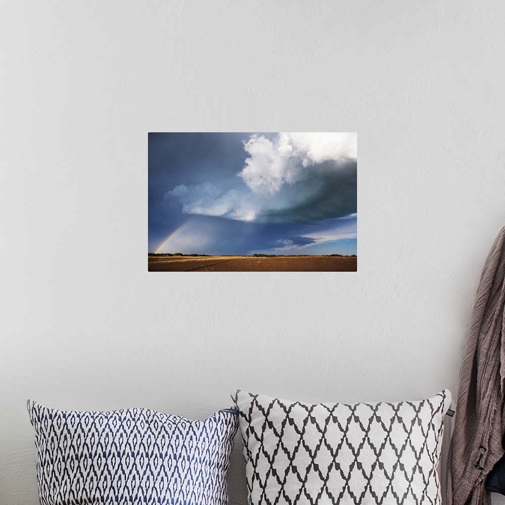 A bohemian room featuring Photograph of a prairie landscape with a rainbow formed underneath dark clouds.