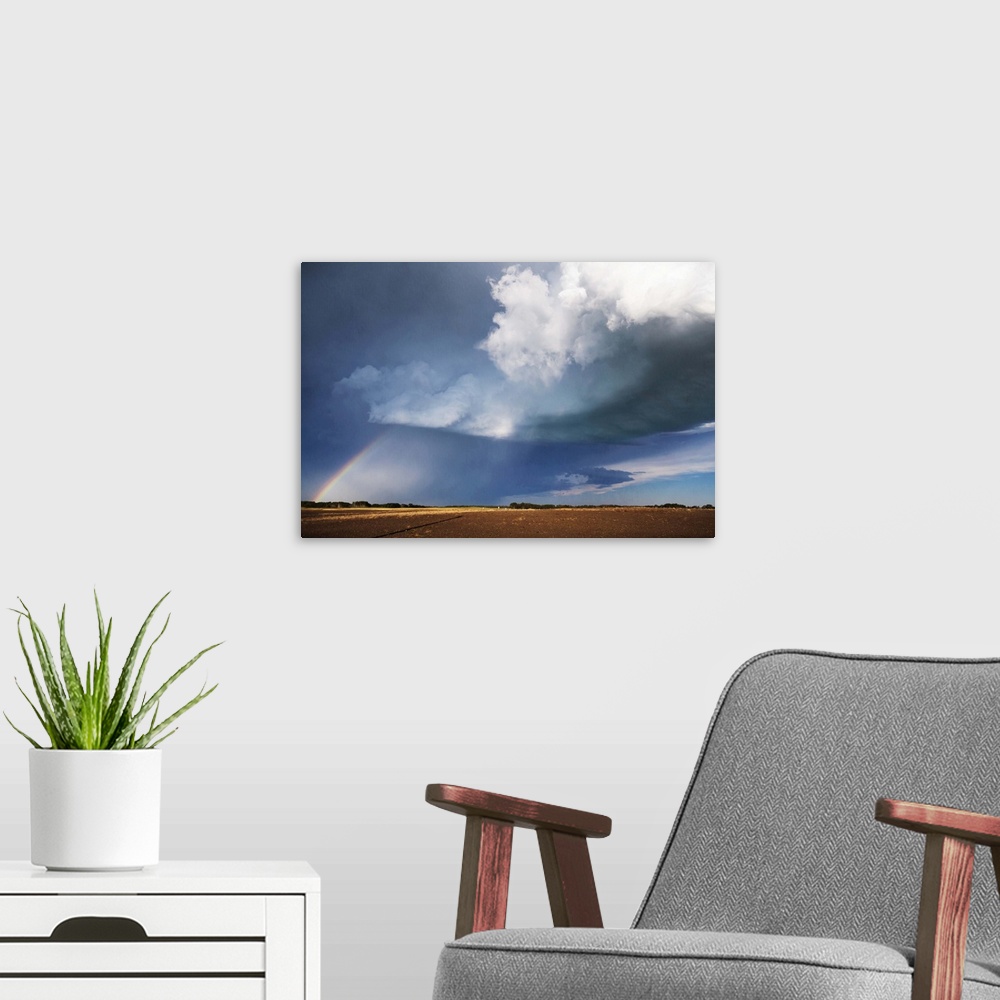 A modern room featuring Photograph of a prairie landscape with a rainbow formed underneath dark clouds.