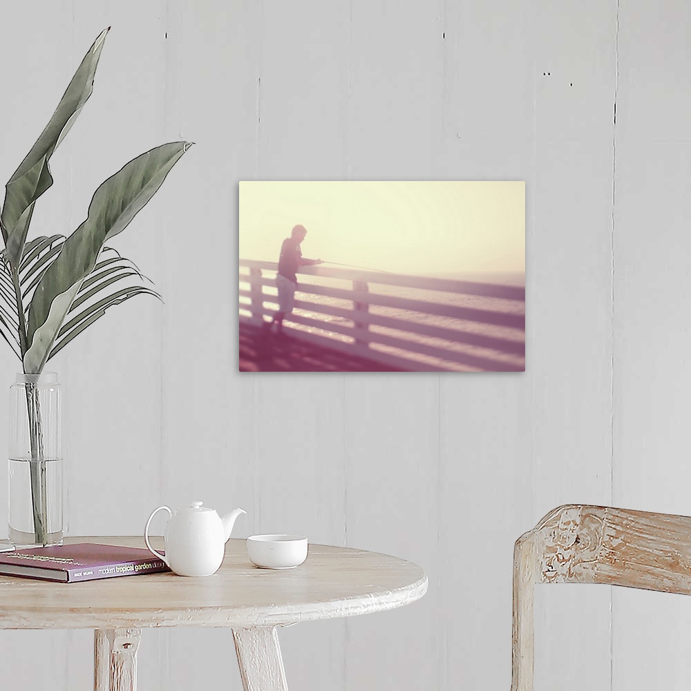 A farmhouse room featuring Pictorialist photo of a person fishing from the pier in the sunshine in pink hues.