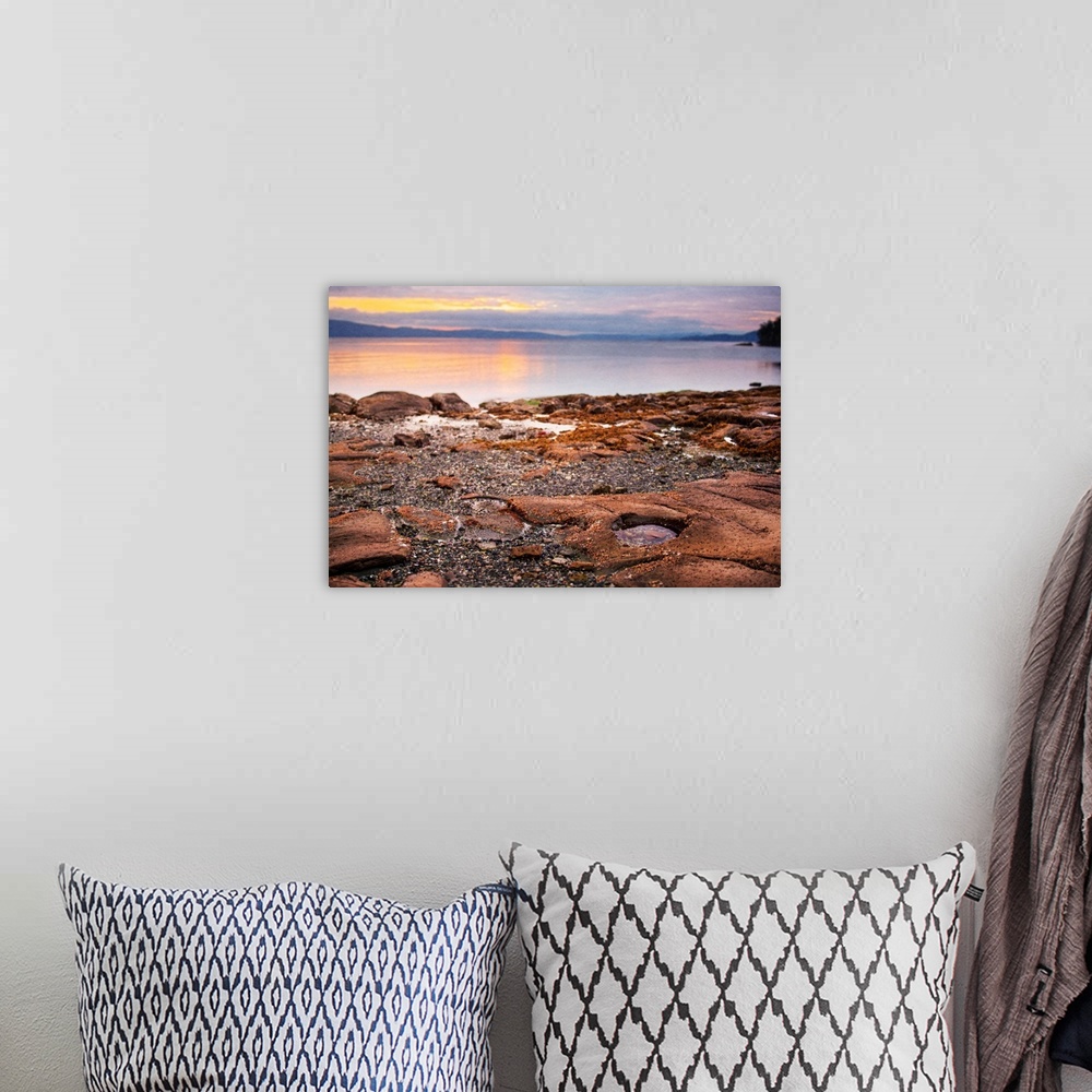 A bohemian room featuring A photograph of a beach with the rocky shore in focus.