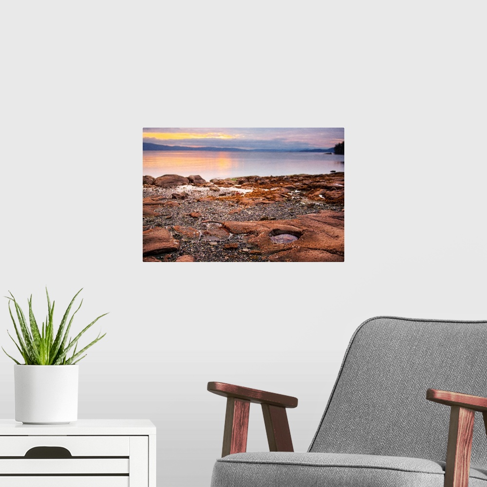 A modern room featuring A photograph of a beach with the rocky shore in focus.