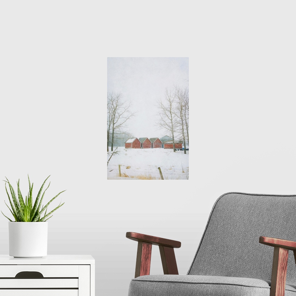 A modern room featuring Pictorialist photo of red granaries on the prairie in winter.