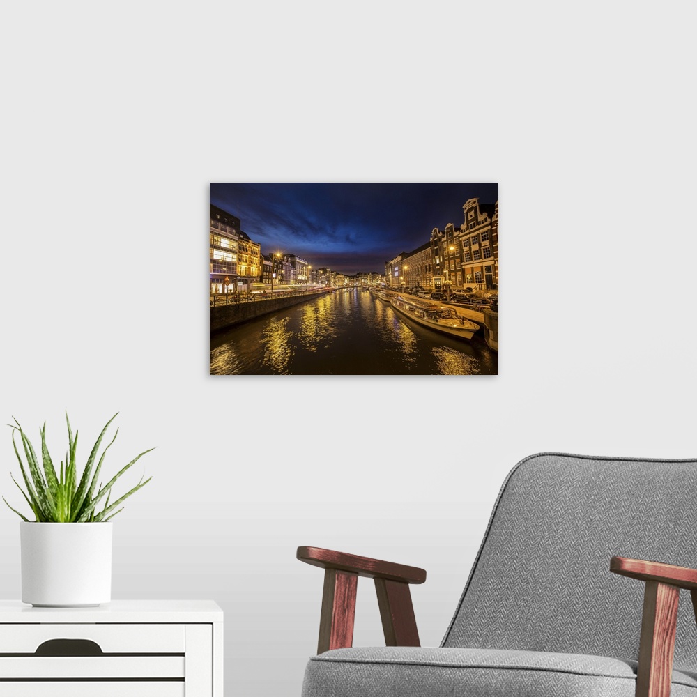 A modern room featuring Boats in the canal in Amsterdam at night.