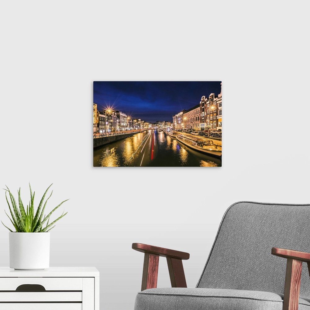 A modern room featuring Boats in the canal at night, reflecting street lights, Amsterdam.