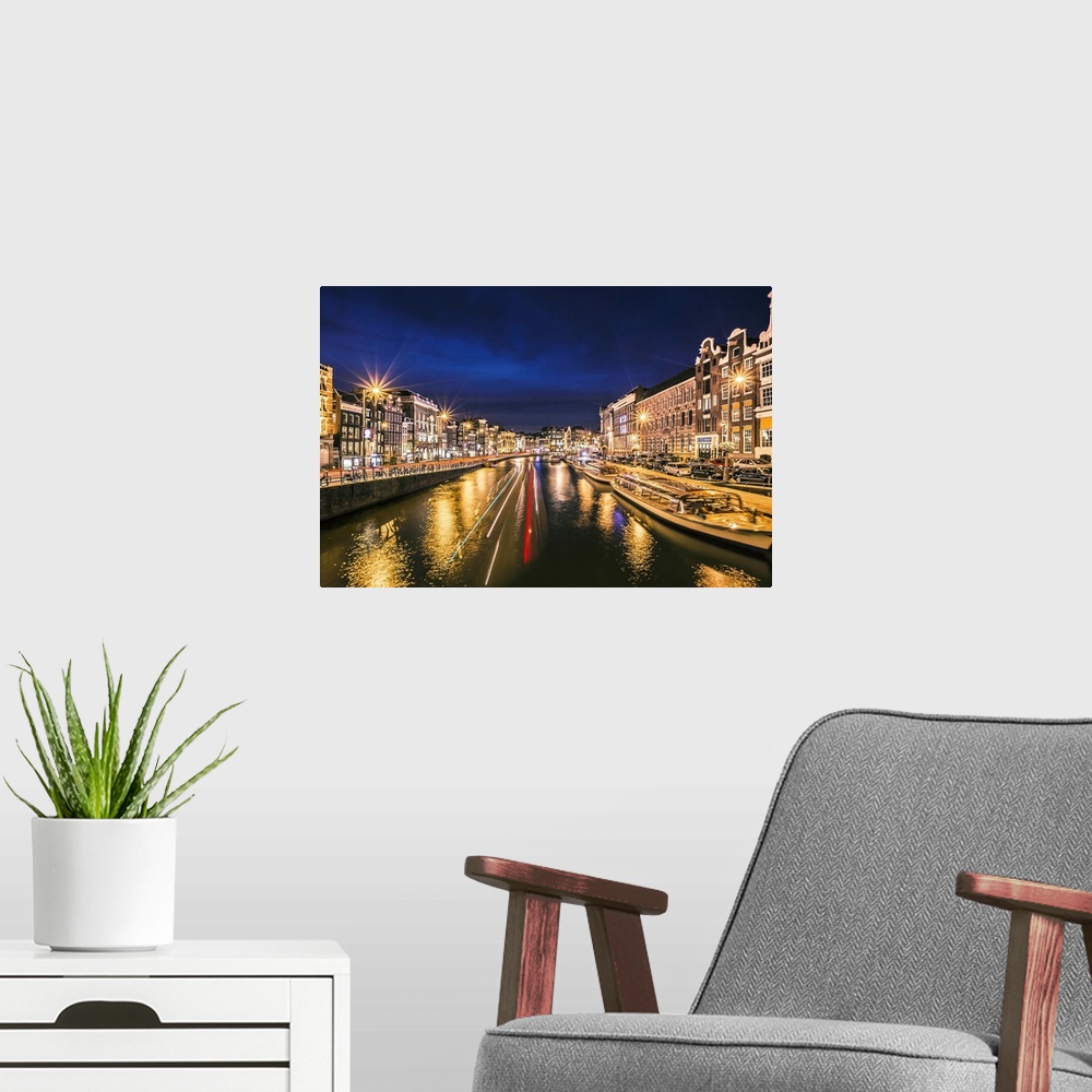 A modern room featuring Boats in the canal at night, reflecting street lights, Amsterdam.