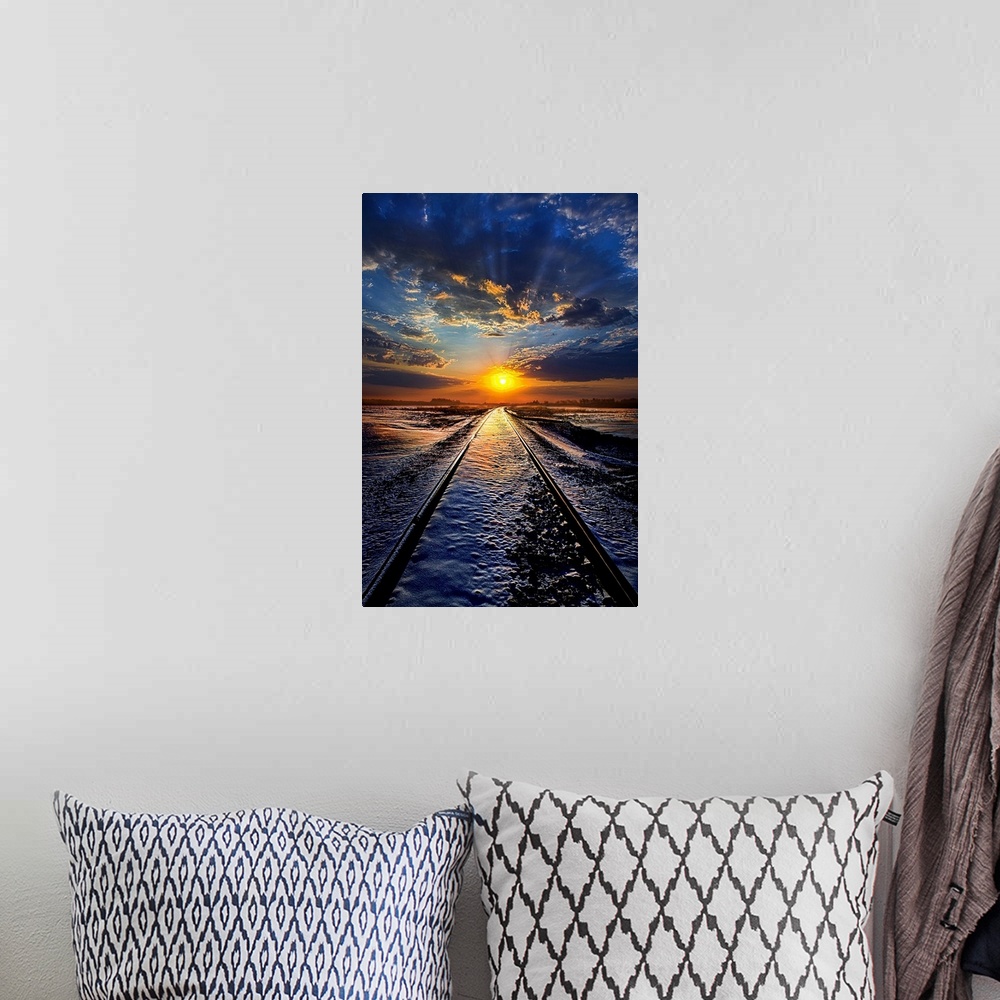 A bohemian room featuring Railroad tracks leading across a snowy field to the sunset on the horizon, with a cloudy sky.