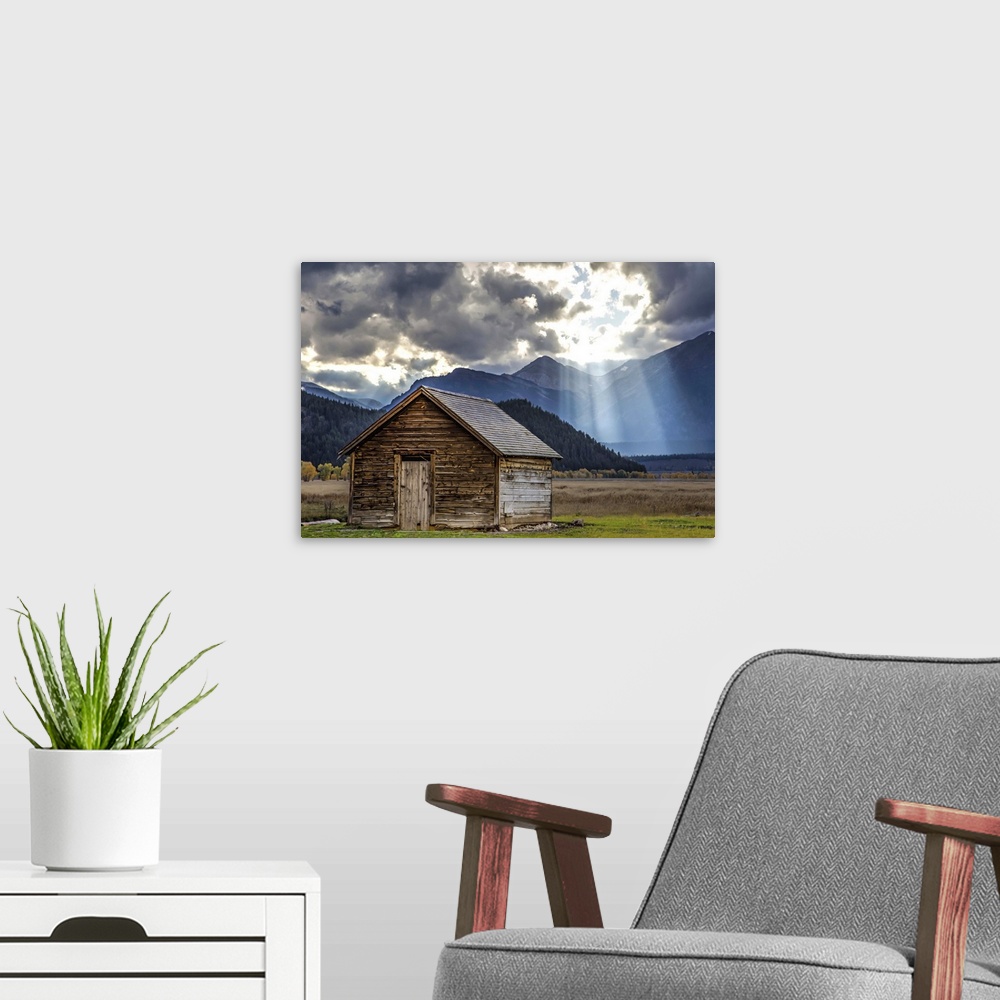A modern room featuring Rays of sunlight shining through the clouds over an old barn in the Grand Teton region, Wyoming.