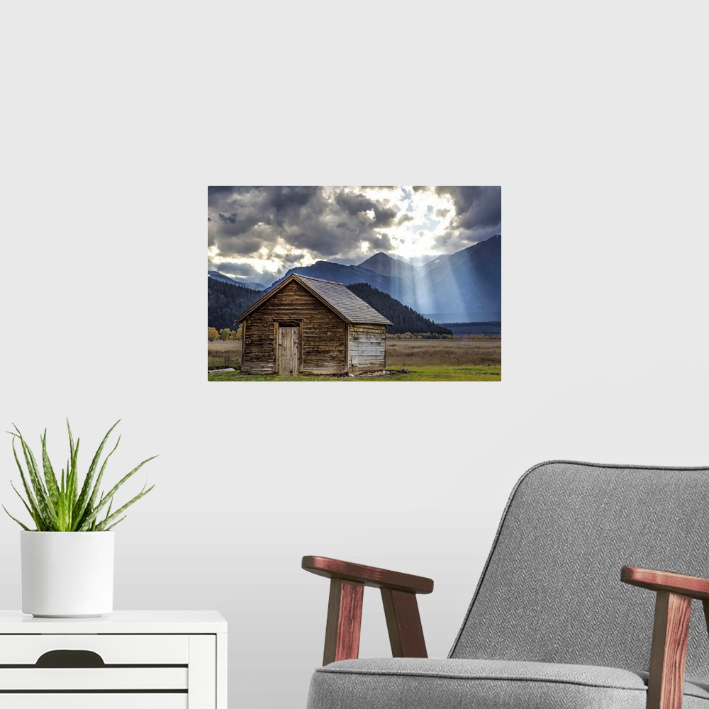 A modern room featuring Rays of sunlight shining through the clouds over an old barn in the Grand Teton region, Wyoming.