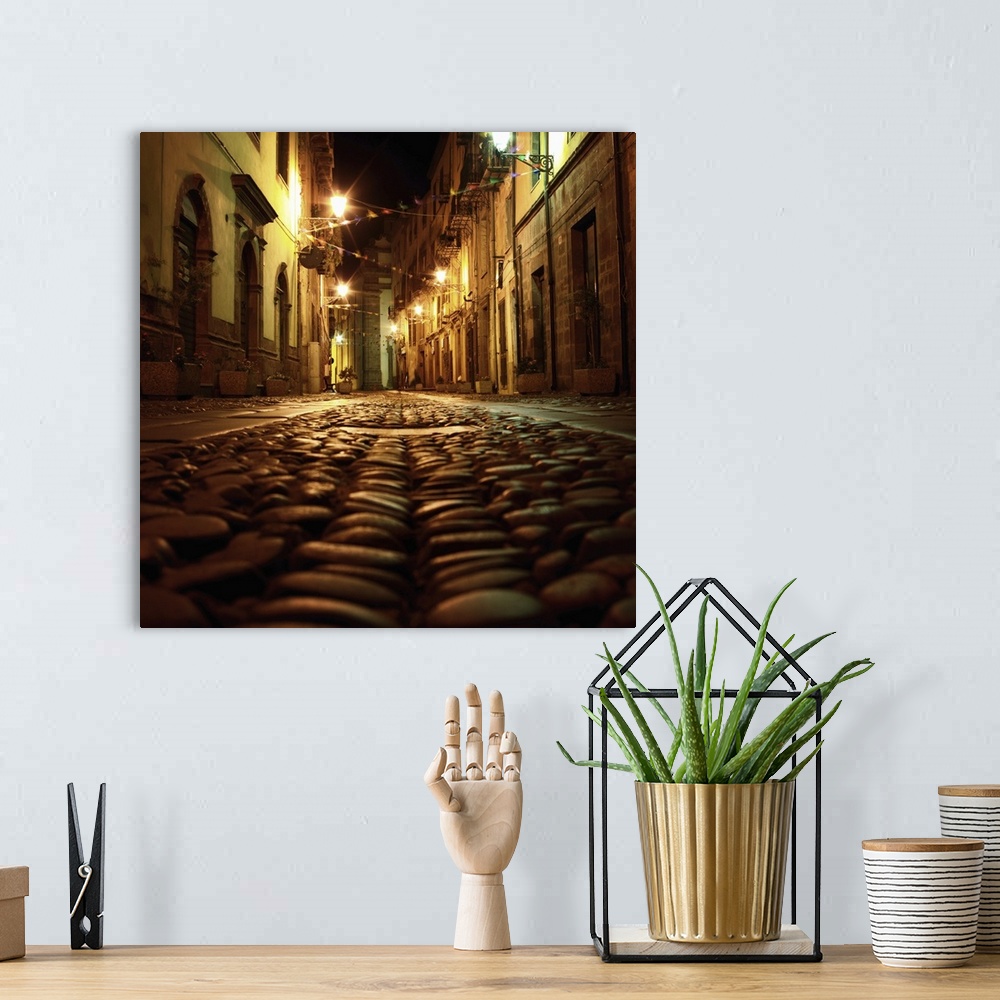 A bohemian room featuring Cobblestone road in the city of Bosa, Italy, at night.
