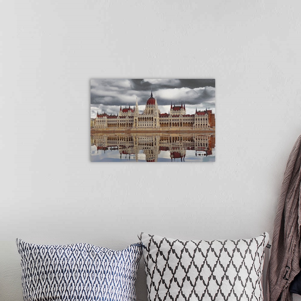 A bohemian room featuring Budapest cityscape reflected in the water of the river below on a cloudy day.