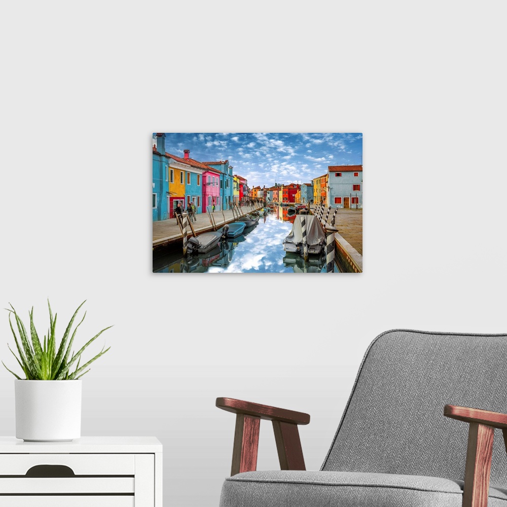 A modern room featuring Colorful buildings along the canal reflecting the clouds above, Italy.
