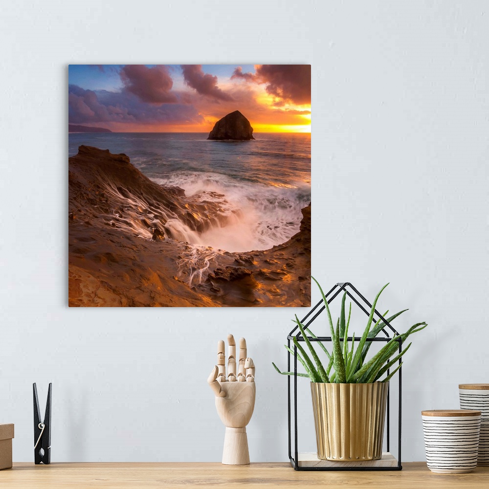 A bohemian room featuring Haystack Rock in the ocean at sunset, seen from the shore at Cape Kiwanda, Oregon.