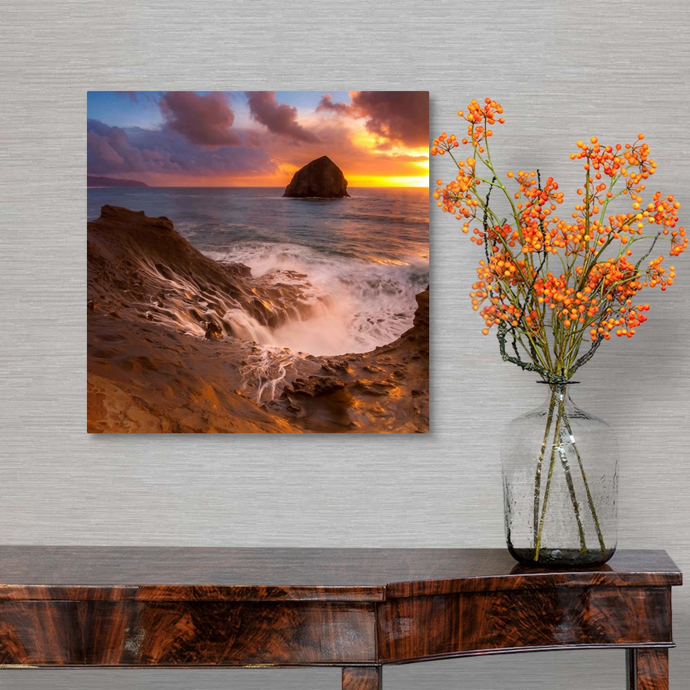 A traditional room featuring Haystack Rock in the ocean at sunset, seen from the shore at Cape Kiwanda, Oregon.