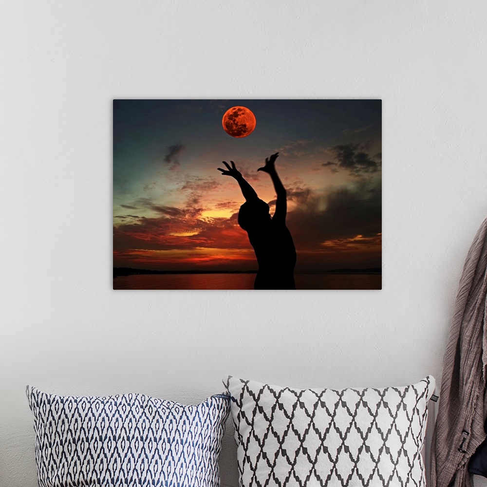 A bohemian room featuring Silhouette of a person with their arms outstretched towards the red moon in the sky.