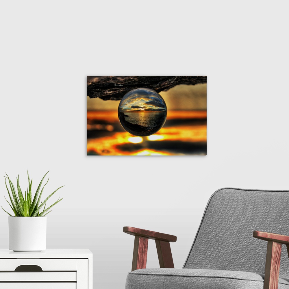 A modern room featuring A sunset seascape reflected right-side-up in an upsidedown glass ball.