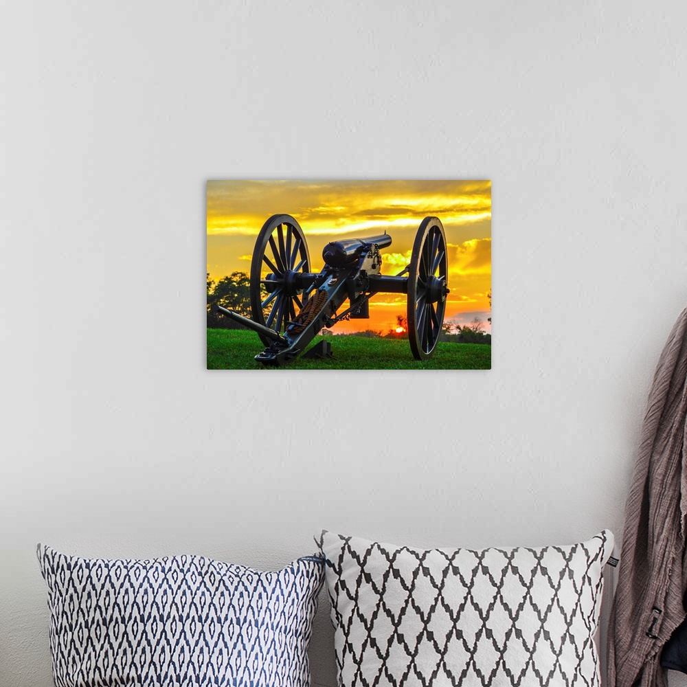 A bohemian room featuring A historical cannon on an old battlefield at sunset.