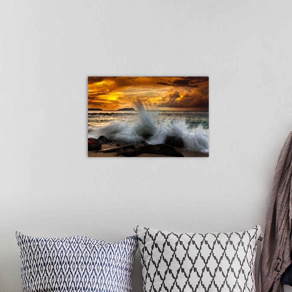 A bohemian room featuring Waves crashing on the rocky shore at sunset.
