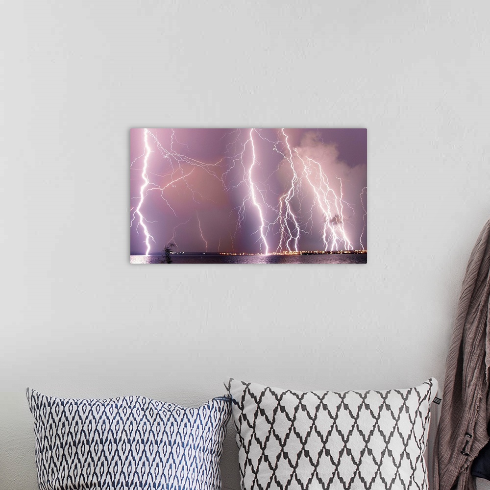 A bohemian room featuring Multiple lightning strikes during a storm over a city.
