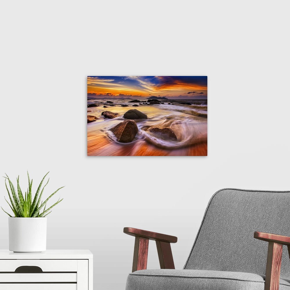 A modern room featuring Beautiful sunset over low tidewater rushing over rocks on the beach.