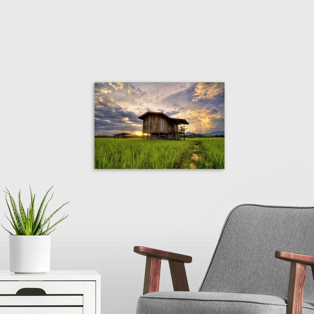 A modern room featuring An old wooden building in a field under a colorful sunset sky.