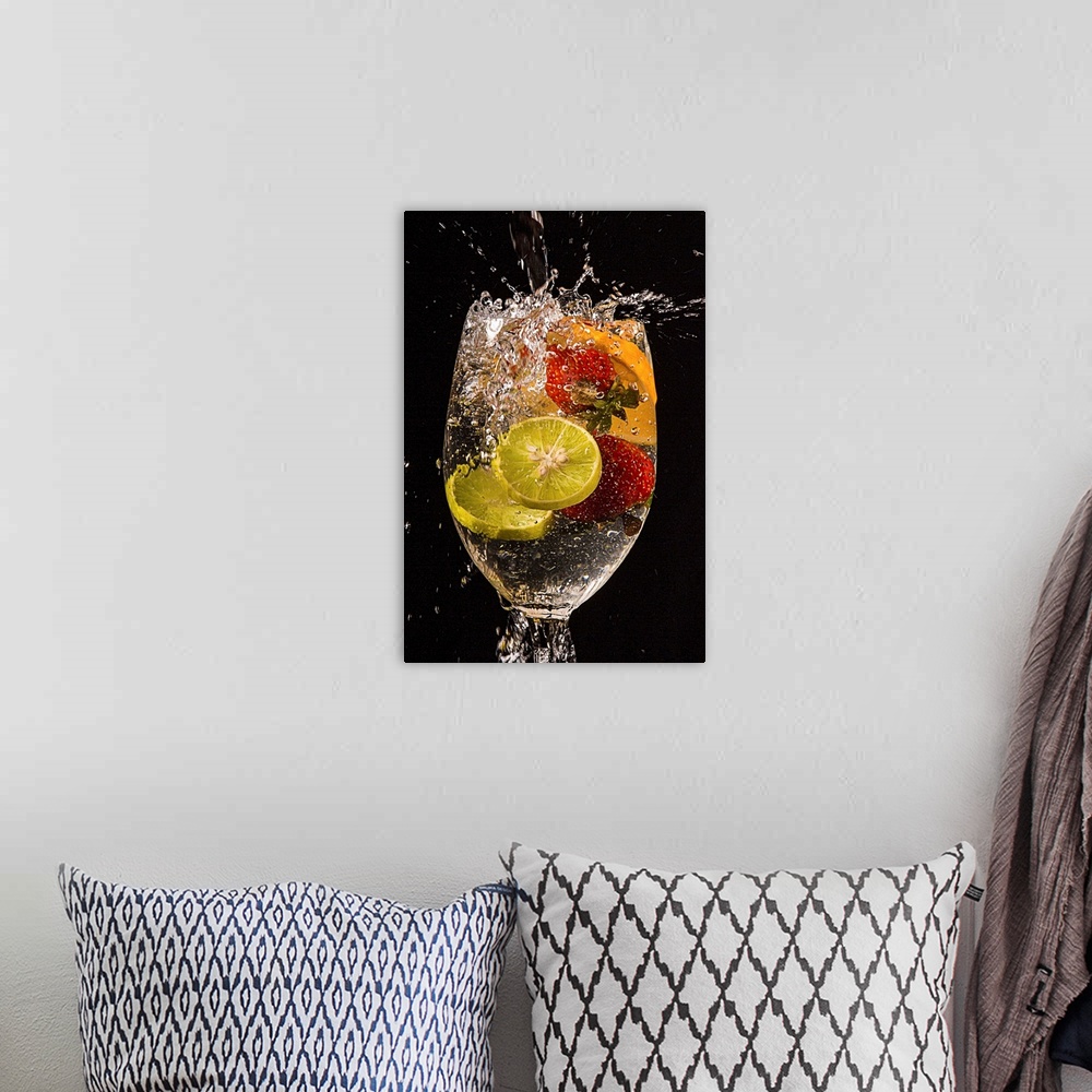 A bohemian room featuring Slices of lemons and oranges and whole strawberries splashing into a glass of water.