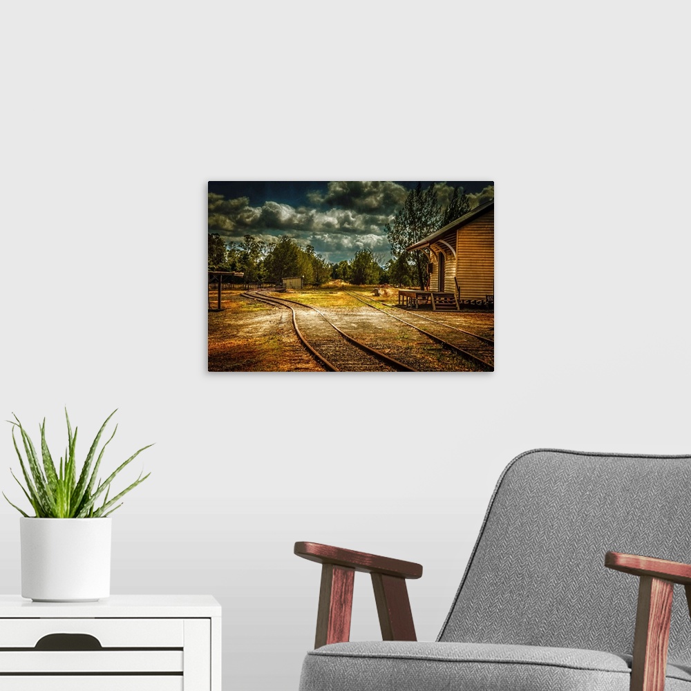 A modern room featuring Train tracks through a village under dark clouds.