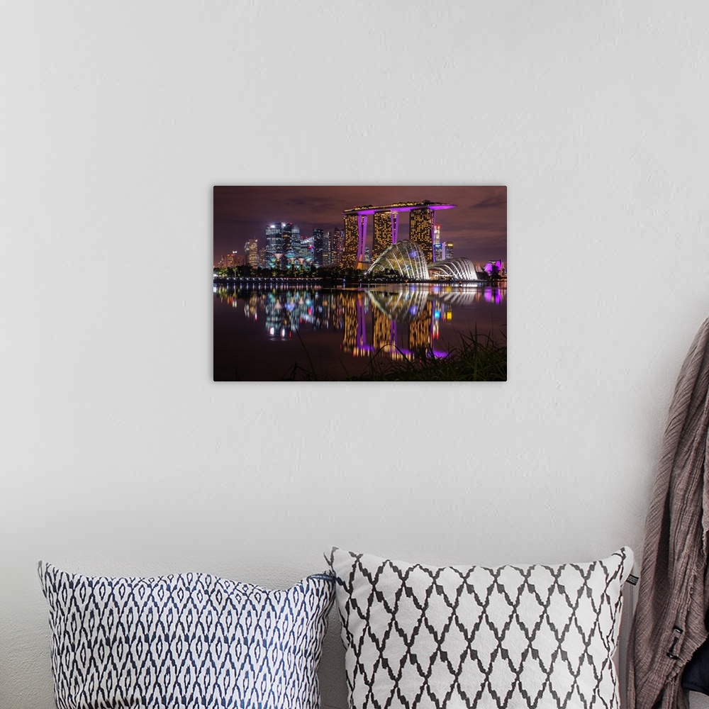 A bohemian room featuring Neon lit skyline of Singapore casting reflection in the water below.