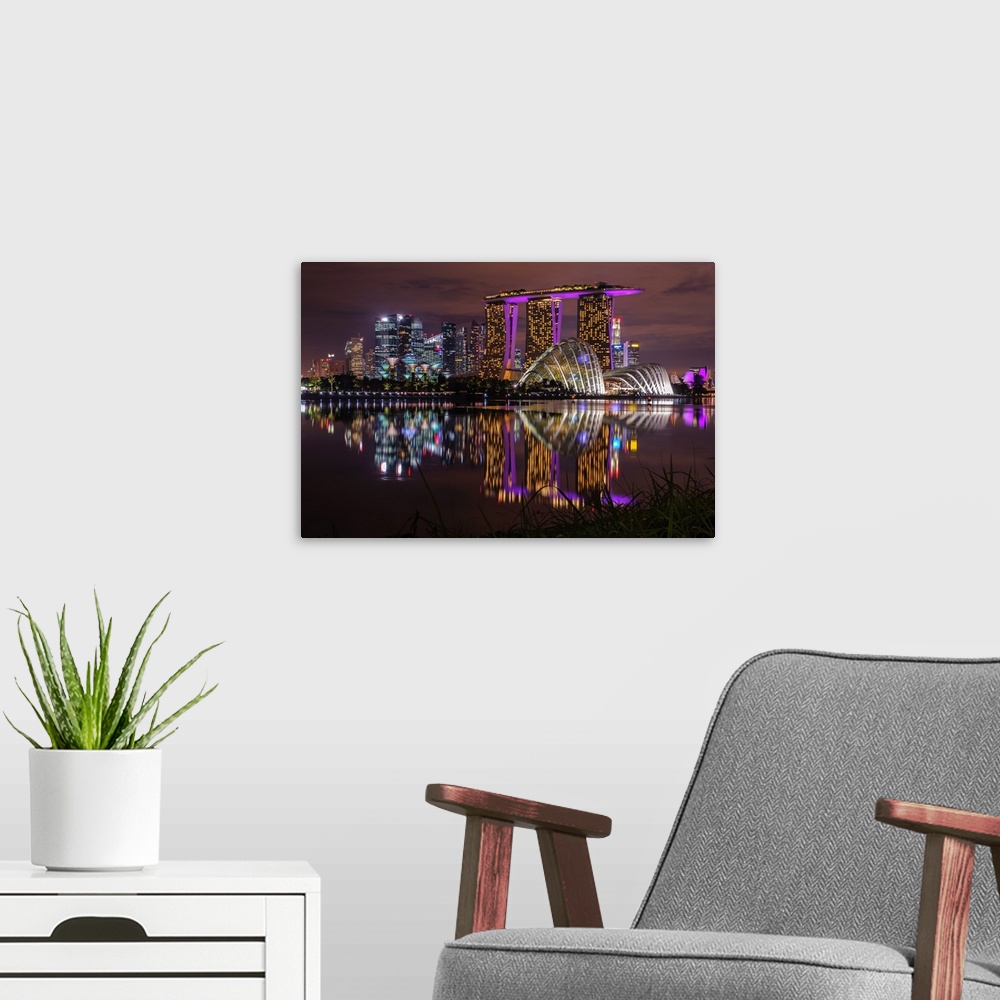 A modern room featuring Neon lit skyline of Singapore casting reflection in the water below.