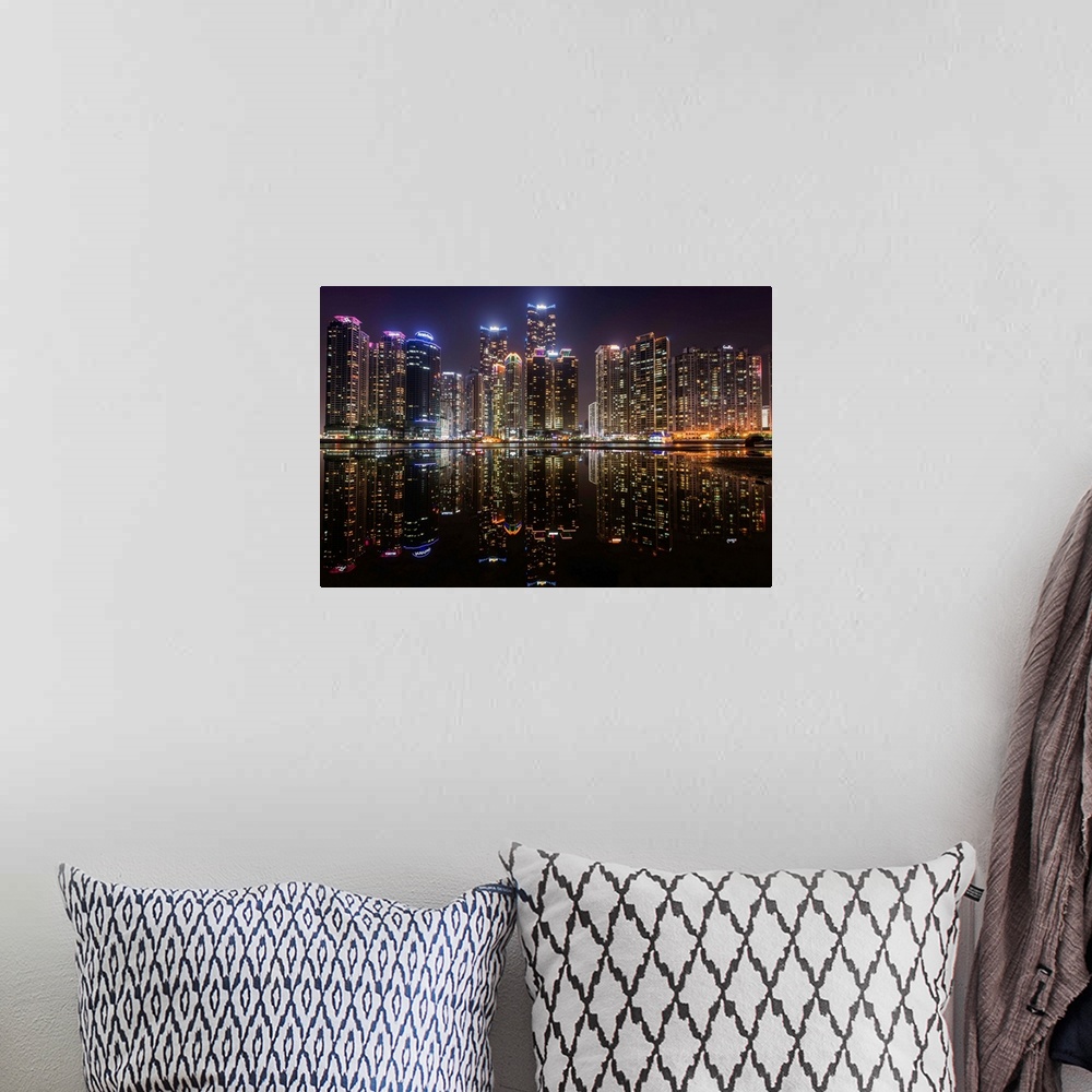 A bohemian room featuring The city of Busan, South Korea, lit up at night, reflected in the water.