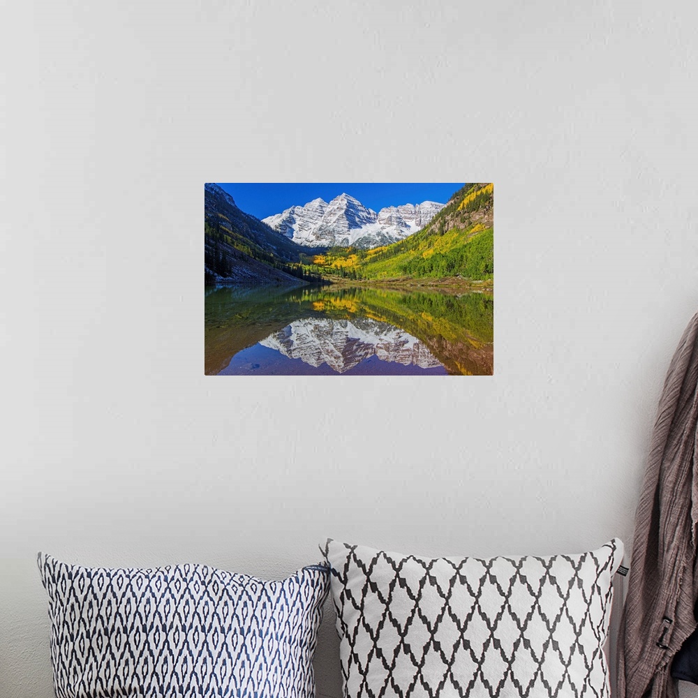 A bohemian room featuring Snowy peaks of the Maroon Bells reflected in the lake below, Colorado.