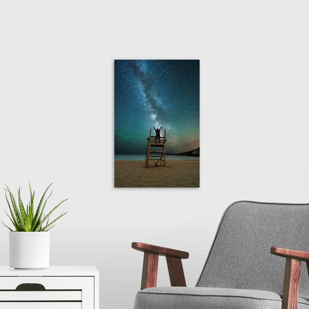 A modern room featuring A photograph of a person on a lifeguard tower under a blanket of star in the night sky.