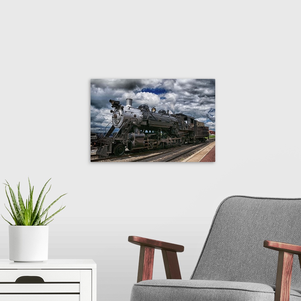 A modern room featuring Photograph of an old steam engine sitting on train train under a dramatic cloudy sky.