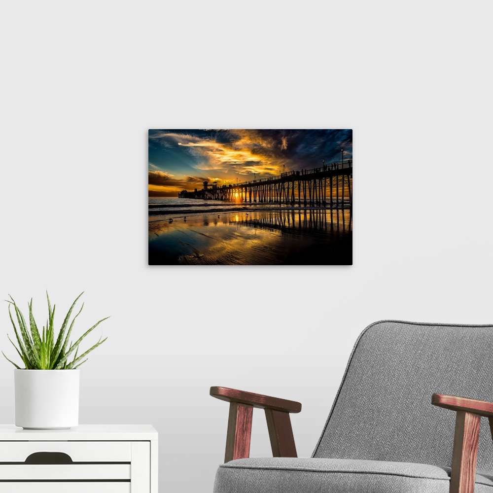 A modern room featuring Oceanside Pier as the sun slips into the Pacific Ocean.