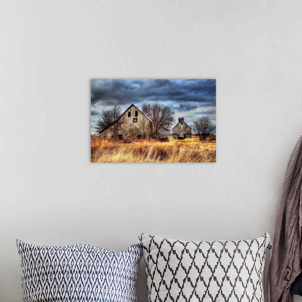 A bohemian room featuring An image of two farm outbuildings under a dark and stormy sky.
