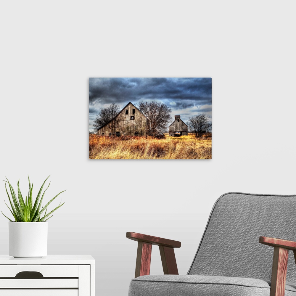 A modern room featuring An image of two farm outbuildings under a dark and stormy sky.
