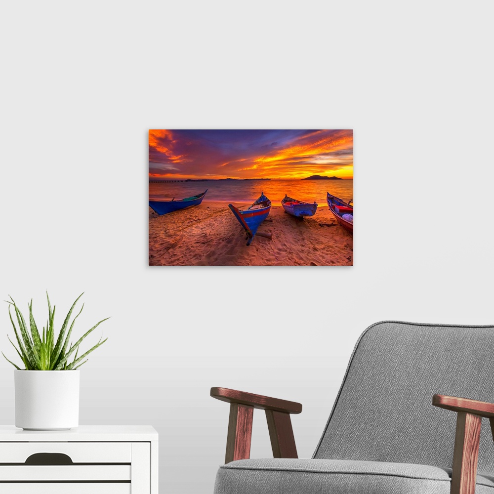 A modern room featuring A row of small blue boats resting on the sandy beach with a brilliant sunrise.