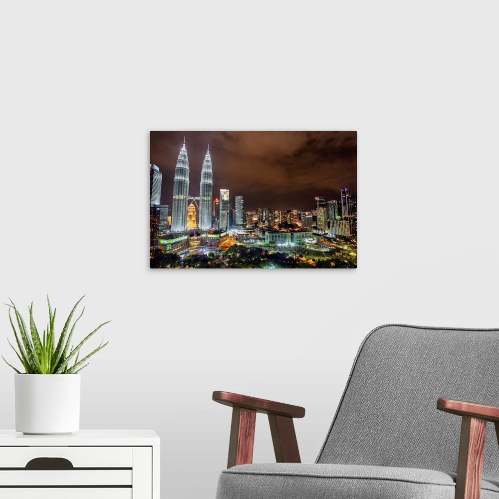 A modern room featuring The Petronas Towers rising above the Kuala Lumpur city skyline at night, Malaysia.