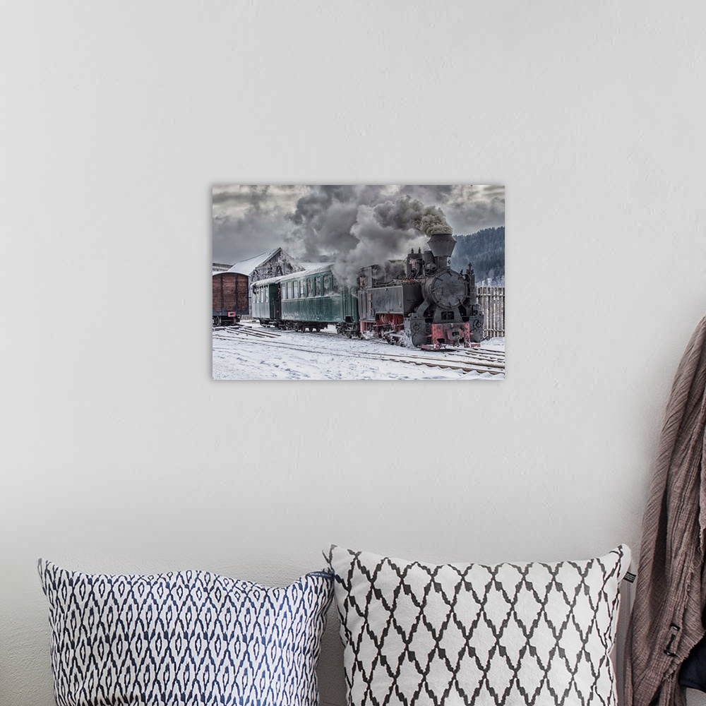 A bohemian room featuring A steam locomotive going down the tracks in the snow.