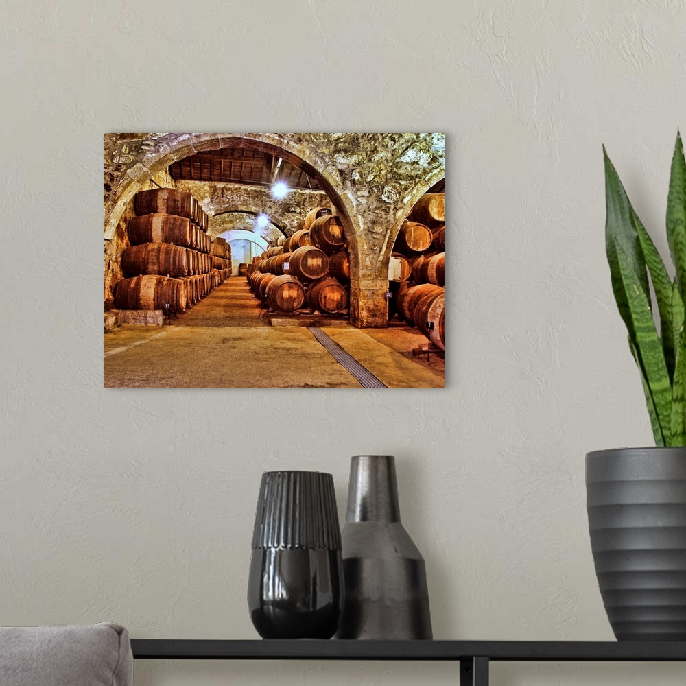 A modern room featuring Stone wine cellar filled with wooden barrels.