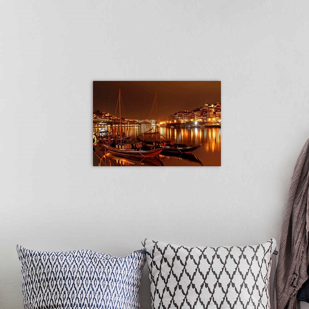 A bohemian room featuring Boats in the River Douro in Porto illuminated with city lights at night.