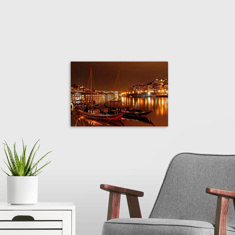 A modern room featuring Boats in the River Douro in Porto illuminated with city lights at night.