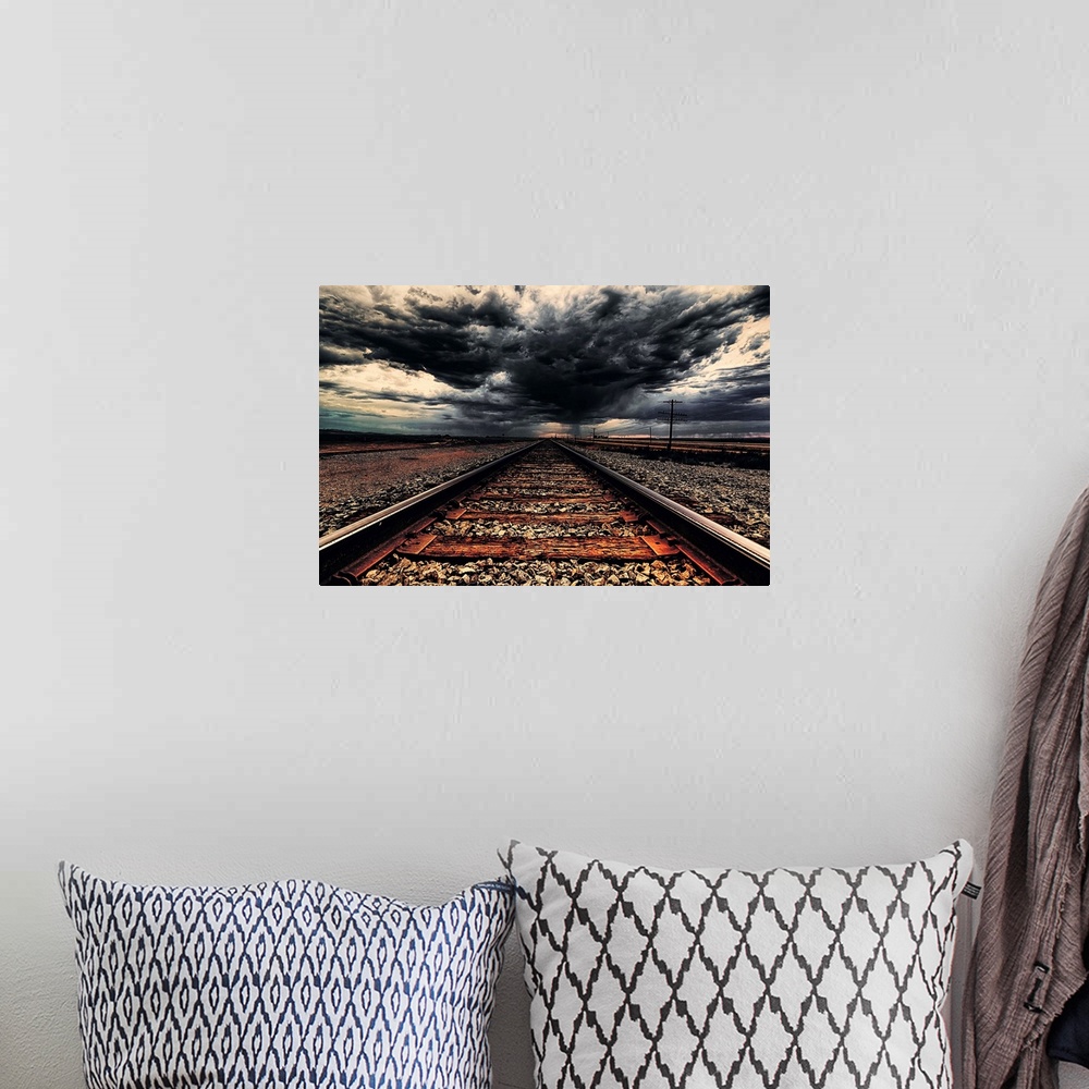 A bohemian room featuring Dark storm clouds over iron railroad tracks.