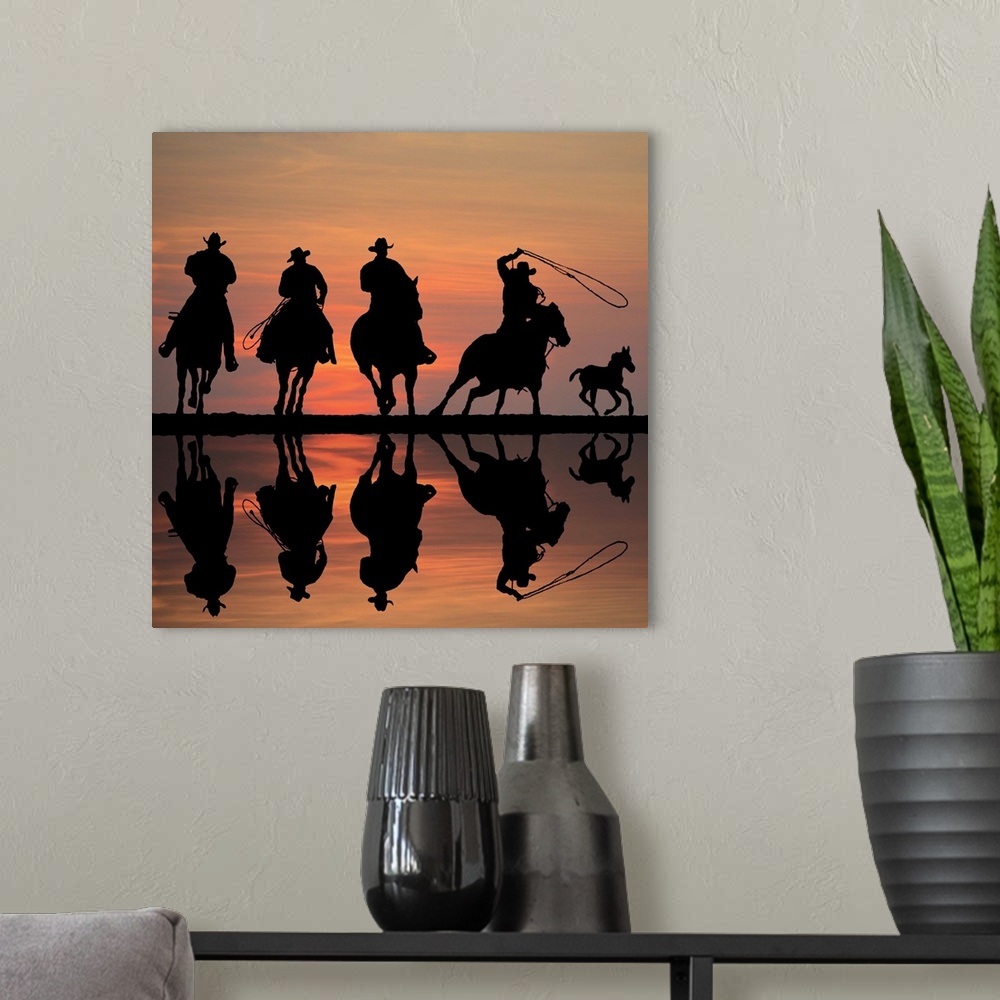A modern room featuring Silhouettes of four cowboys on horseback at sunset, roping a foal.