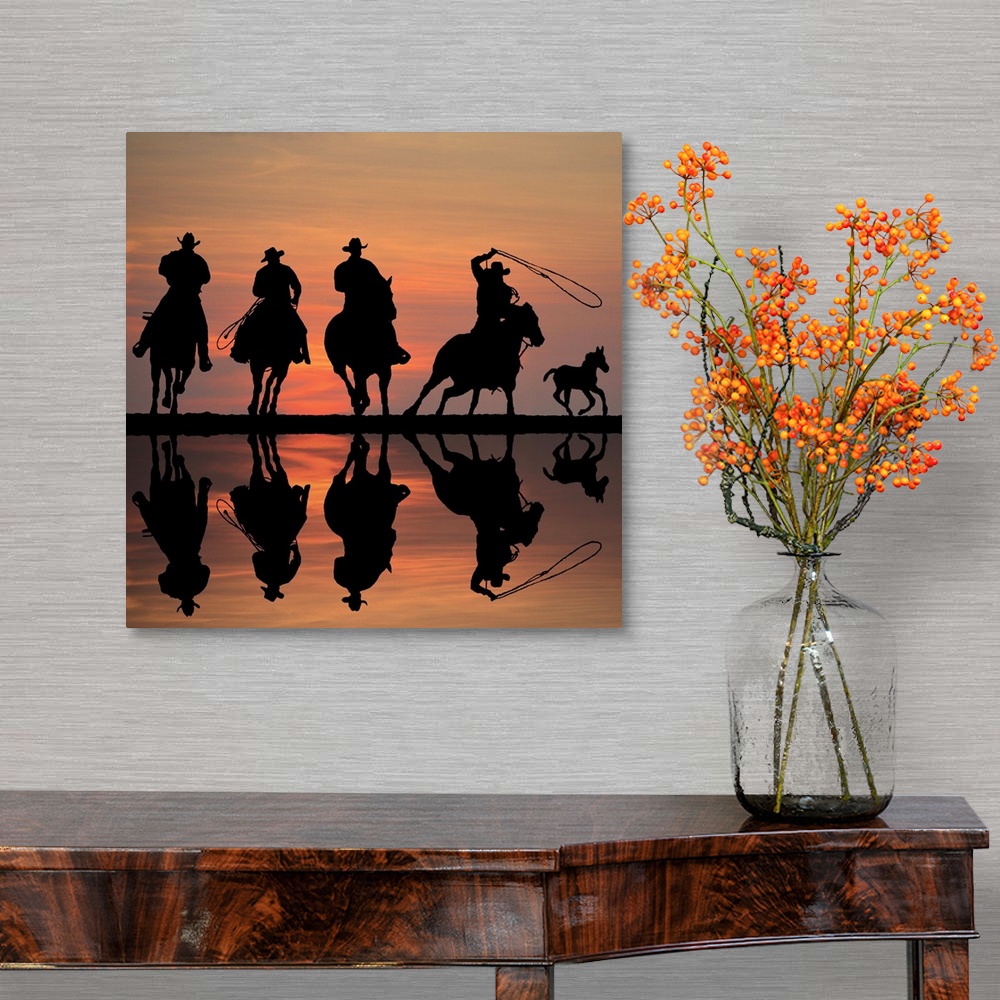 A traditional room featuring Silhouettes of four cowboys on horseback at sunset, roping a foal.