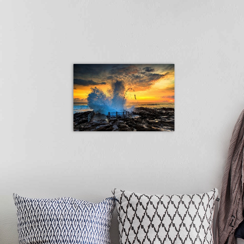 A bohemian room featuring Waves crashing onto the rocky shore at sunset.