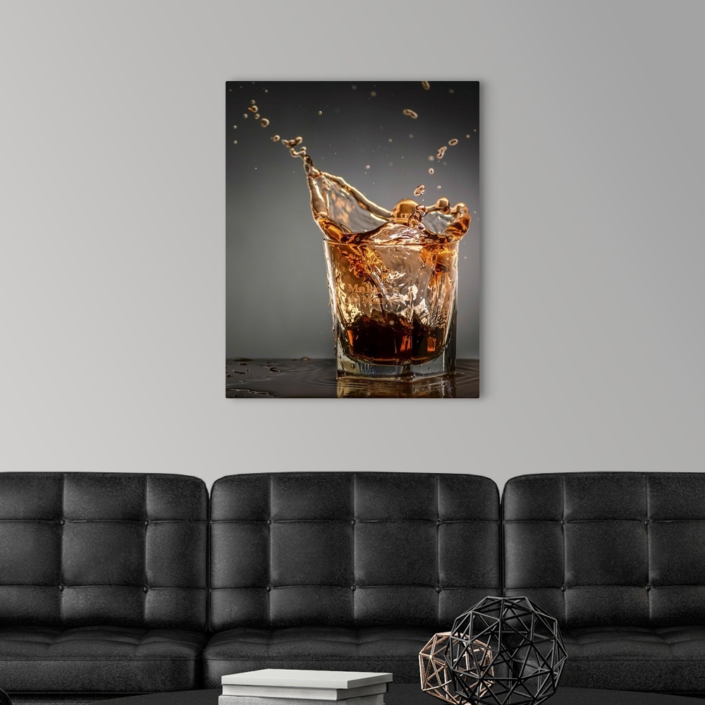 A modern room featuring Amber colored bourbon splashing in a short glass.
